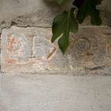 Veniamo attratti da una piccola lastra in pietra con caratteri rossi che si trova sulla finestrella. A prima vista leggiamo una data, il 1701, forse l�anno dell�edificazione della chiesa. Ma potrebbero essere anche lettere dell�alfabeto greco: sembra l�acronimo ΙΧΘΥΣ, che veniva usato ai primordi del Cristianesimo per indicare Ges�